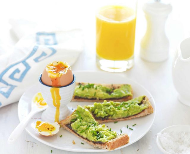 Café da manhã com ovos cozidos, abacate e suco de laranja
